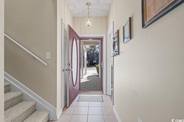 entryway with light tile patterned floors, stairs, baseboards, and a chandelier