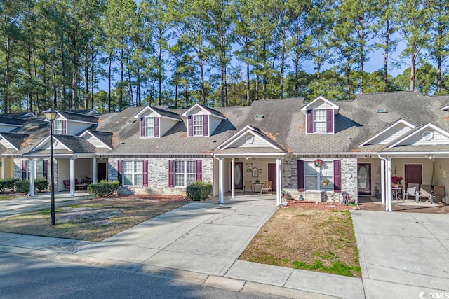 view of front of home with a porch, roof with shingles, and brick siding