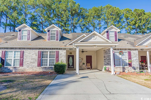 view of front of property with concrete driveway, brick siding, ceiling fan, and roof with shingles