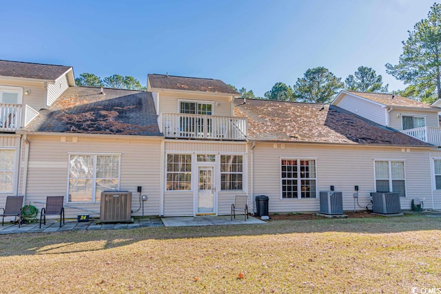 back of house featuring central air condition unit, a balcony, a patio area, and a yard