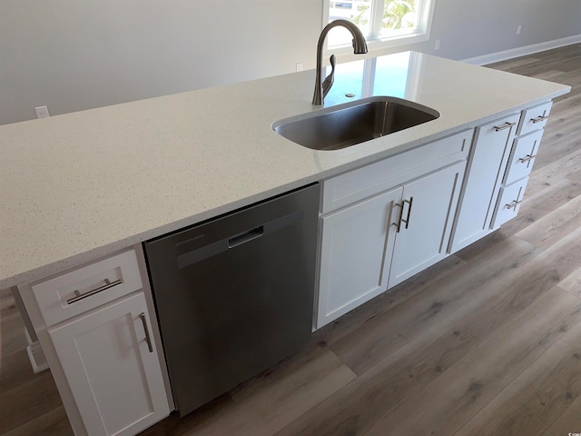 kitchen with stainless steel dishwasher, sink, white cabinetry, and wood-type flooring