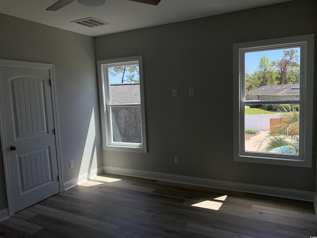 spare room featuring a healthy amount of sunlight, ceiling fan, and dark hardwood / wood-style flooring