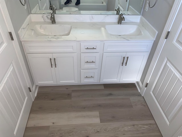 bathroom with oversized vanity, wood-type flooring, and dual sinks