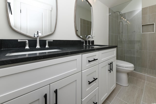 bathroom featuring tiled shower, vanity, toilet, and tile patterned flooring