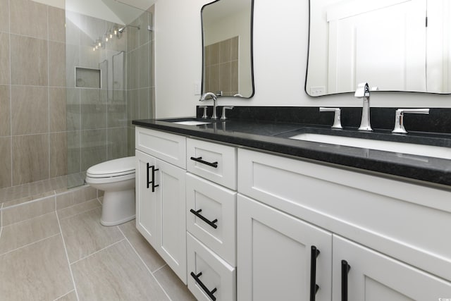 bathroom featuring tile patterned floors, vanity, toilet, and a tile shower