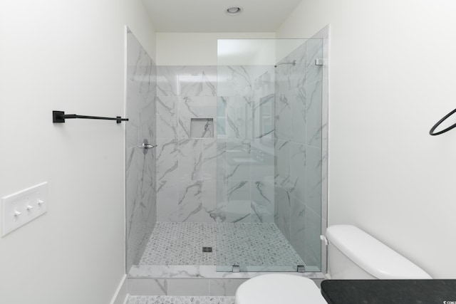 bathroom with a tile shower and toilet