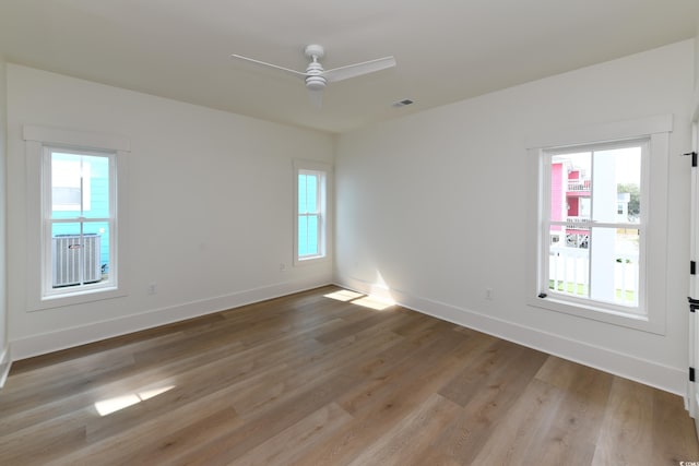 spare room featuring ceiling fan, light hardwood / wood-style floors, and a healthy amount of sunlight