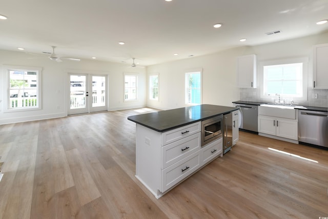 kitchen with appliances with stainless steel finishes, light wood-type flooring, decorative backsplash, and white cabinets