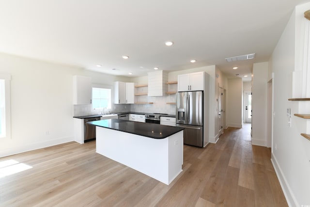 kitchen with tasteful backsplash, stainless steel appliances, a kitchen island, and white cabinets