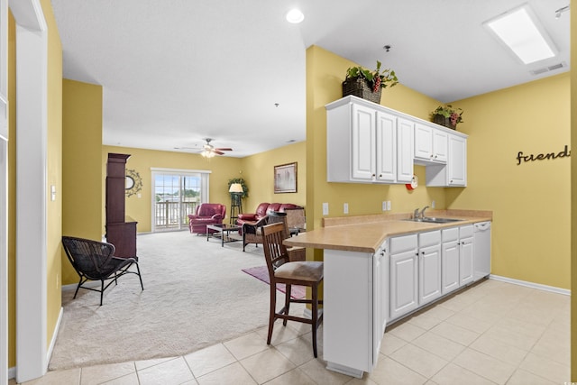 kitchen featuring ceiling fan, sink, kitchen peninsula, and white cabinetry