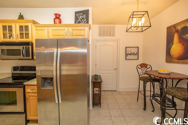 kitchen with a chandelier, light brown cabinetry, stainless steel appliances, hanging light fixtures, and light tile flooring