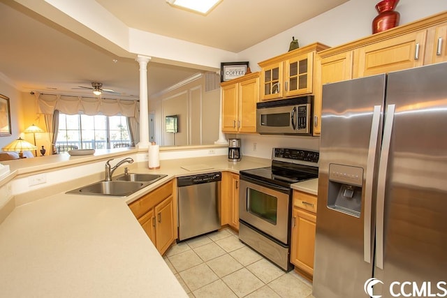 kitchen with appliances with stainless steel finishes, light tile floors, ceiling fan, sink, and decorative columns