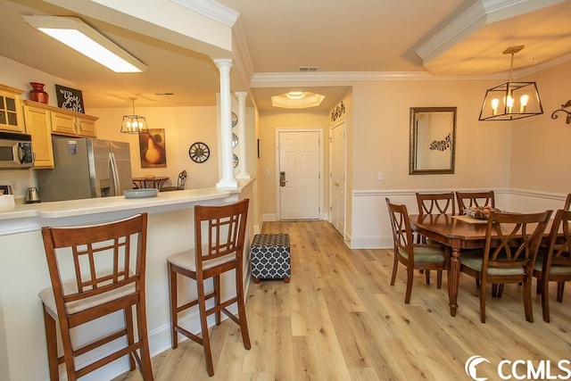 dining room with ornamental molding, a chandelier, light hardwood / wood-style floors, and decorative columns