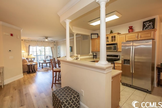 kitchen with appliances with stainless steel finishes, light wood-type flooring, ceiling fan, a breakfast bar area, and decorative columns