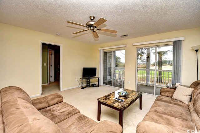 living room featuring a textured ceiling, ceiling fan, and light colored carpet