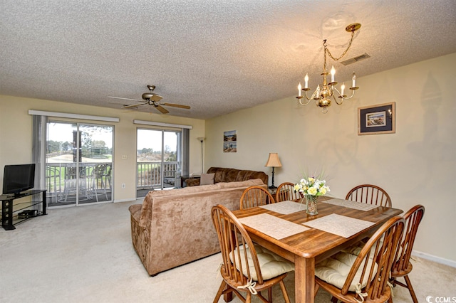 dining area featuring a textured ceiling, light colored carpet, and ceiling fan with notable chandelier