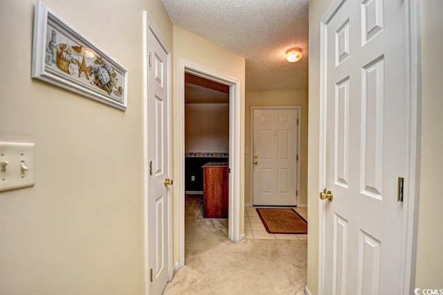 hall featuring light colored carpet and a textured ceiling