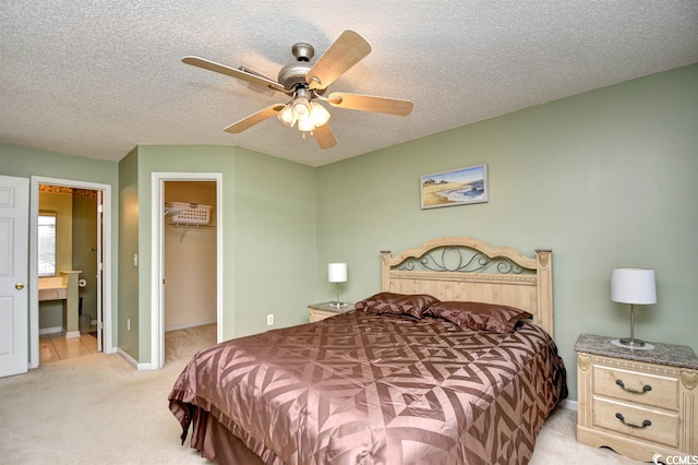 bedroom featuring light carpet, a closet, ceiling fan, a textured ceiling, and a walk in closet