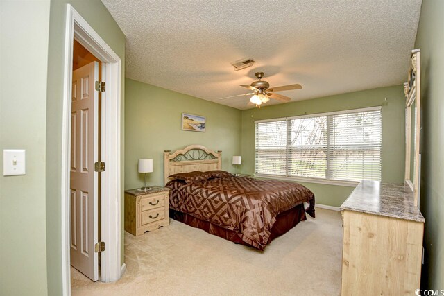 carpeted bedroom with ceiling fan and a textured ceiling