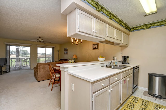 kitchen with light tile floors, a textured ceiling, kitchen peninsula, ceiling fan with notable chandelier, and sink