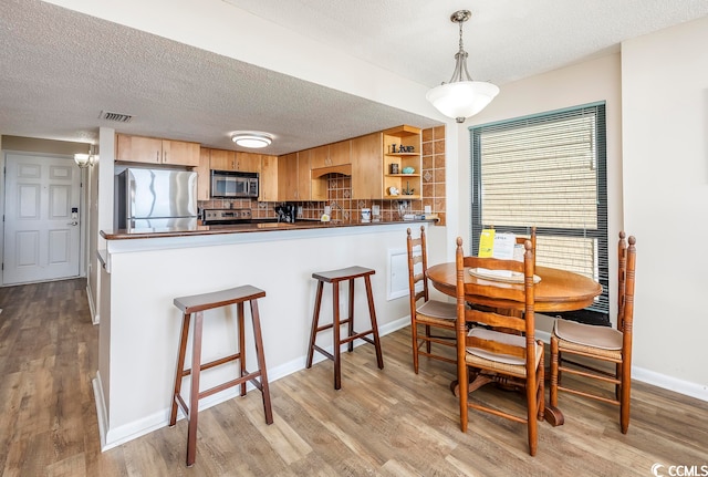 dining room with light hardwood / wood-style flooring and a textured ceiling