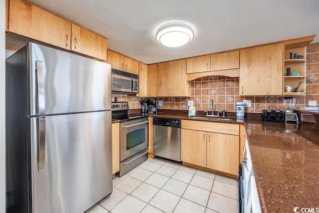 kitchen with backsplash, a textured ceiling, appliances with stainless steel finishes, and sink