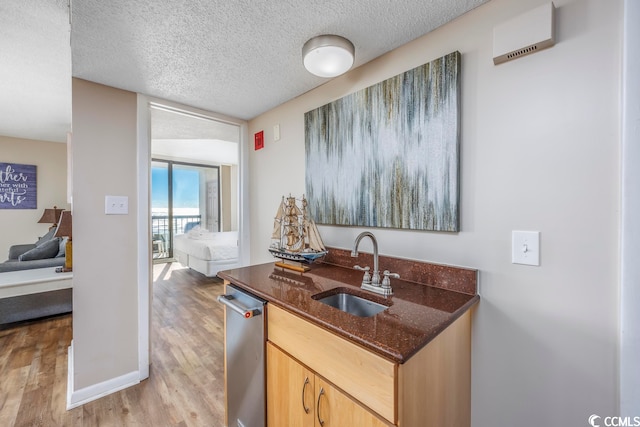 kitchen featuring light brown cabinets, a textured ceiling, light hardwood / wood-style flooring, and sink