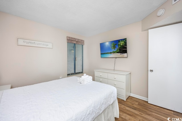 bedroom with light wood-type flooring and a textured ceiling