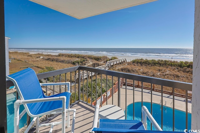 balcony with a water view and a view of the beach