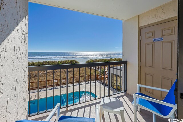 balcony with a water view and a view of the beach