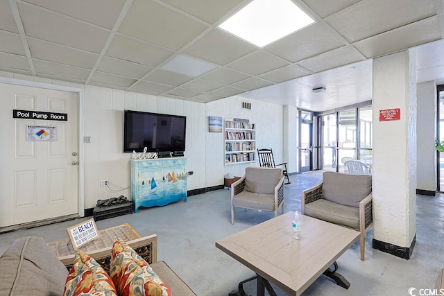 living room featuring concrete flooring and a drop ceiling