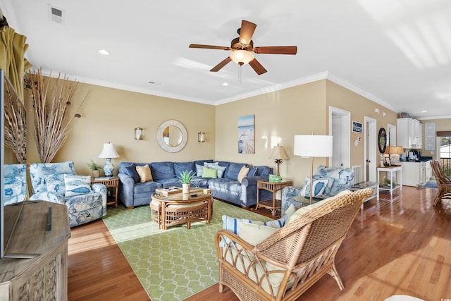 living room featuring light hardwood / wood-style floors, ceiling fan, and crown molding