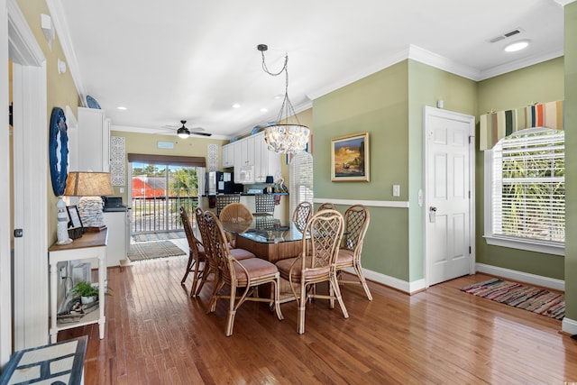 dining area featuring hardwood / wood-style flooring, ceiling fan with notable chandelier, and crown molding