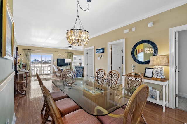 dining area with wood-type flooring, ceiling fan with notable chandelier, and ornamental molding