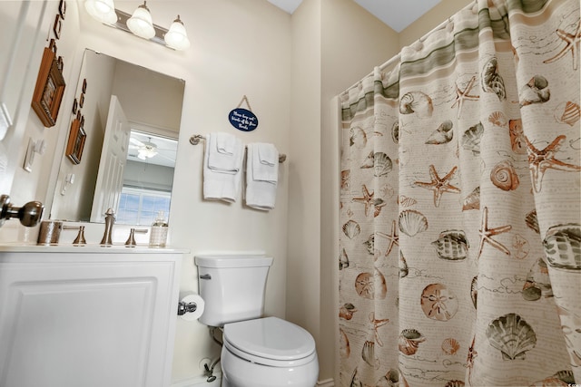 bathroom with walk in shower, ceiling fan, vanity, and toilet