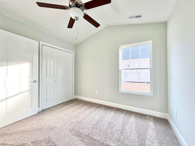 unfurnished bedroom featuring a closet, carpet flooring, vaulted ceiling, and ceiling fan