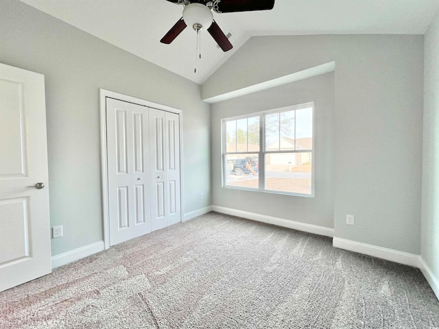 unfurnished bedroom featuring lofted ceiling, a closet, carpet, and ceiling fan