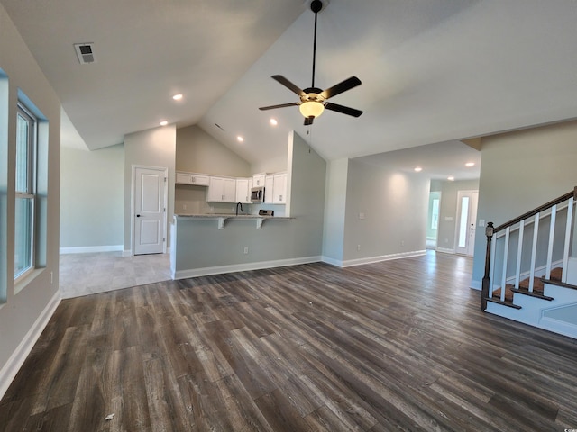 unfurnished living room with lofted ceiling, sink, dark wood-type flooring, and ceiling fan