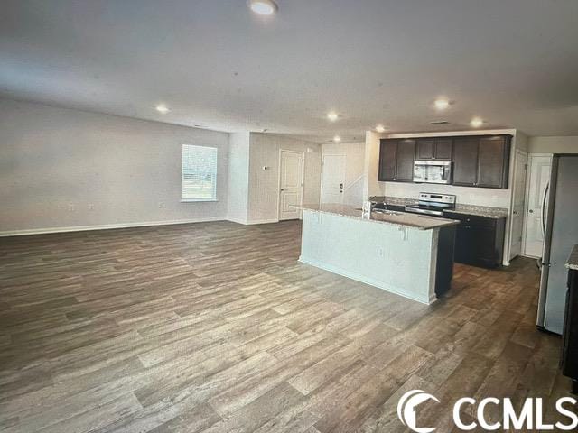 kitchen featuring an island with sink, dark brown cabinets, appliances with stainless steel finishes, and dark hardwood / wood-style flooring