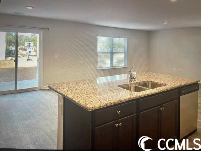 kitchen featuring dishwasher, light stone counters, a wealth of natural light, and dark brown cabinetry