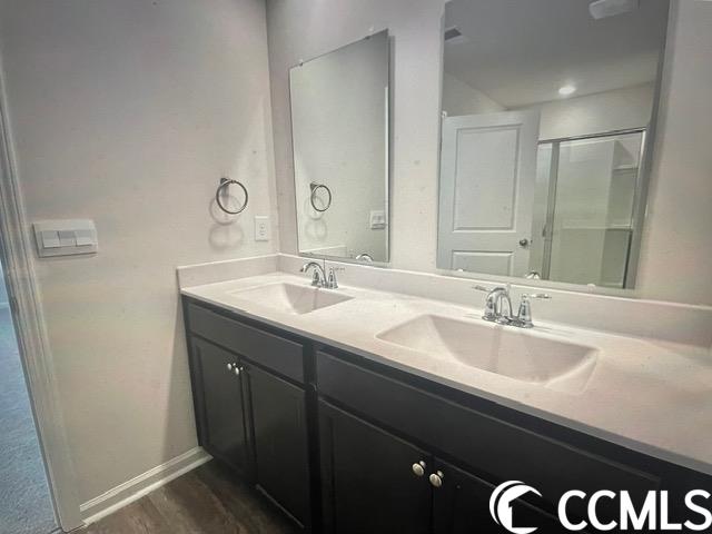 bathroom with double vanity and wood-type flooring