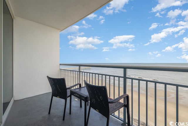 balcony with a water view and a view of the beach