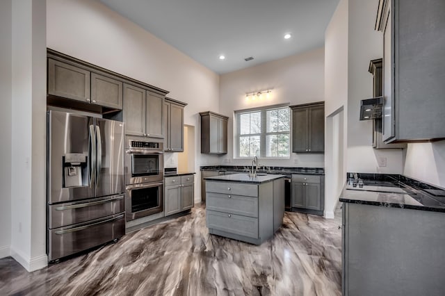 kitchen featuring stainless steel appliances, dark hardwood / wood-style flooring, a center island, and dark stone counters