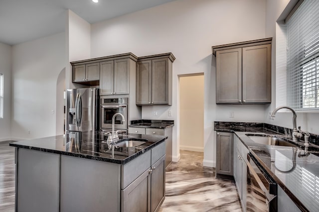 kitchen featuring dark stone counters, stainless steel appliances, light hardwood / wood-style floors, and sink