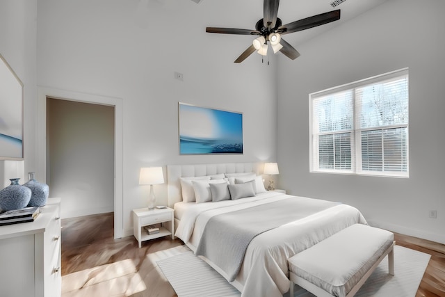 bedroom featuring hardwood / wood-style floors, a high ceiling, and ceiling fan