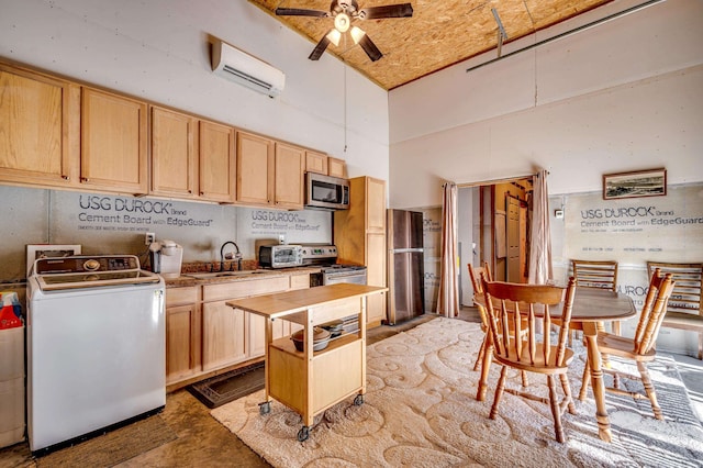 kitchen featuring light brown cabinetry, washer / clothes dryer, a wall unit AC, sink, and appliances with stainless steel finishes