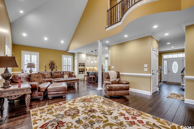 living room with dark hardwood / wood-style floors, high vaulted ceiling, ornamental molding, and ornate columns