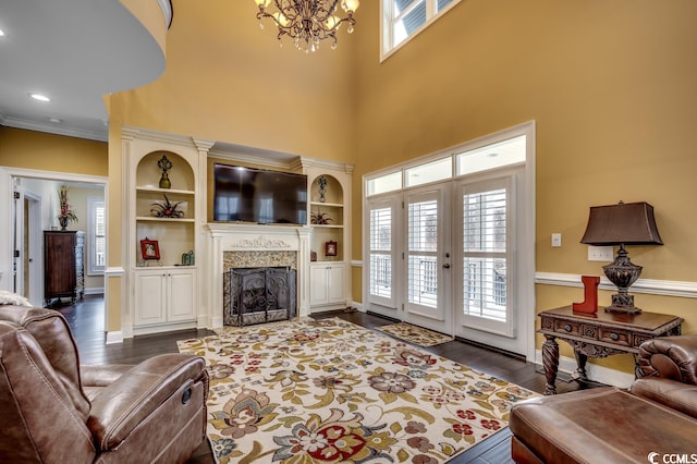 living room with built in features, crown molding, dark hardwood / wood-style floors, and a chandelier