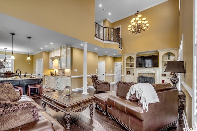 living room with dark wood-type flooring, decorative columns, a chandelier, and a towering ceiling