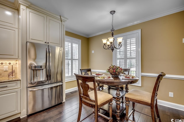 dining area featuring dark hardwood / wood-style flooring, ornamental molding, and a chandelier